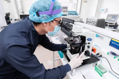 Profesional de salud analizando muestras en microscopio de laboratorio clínico